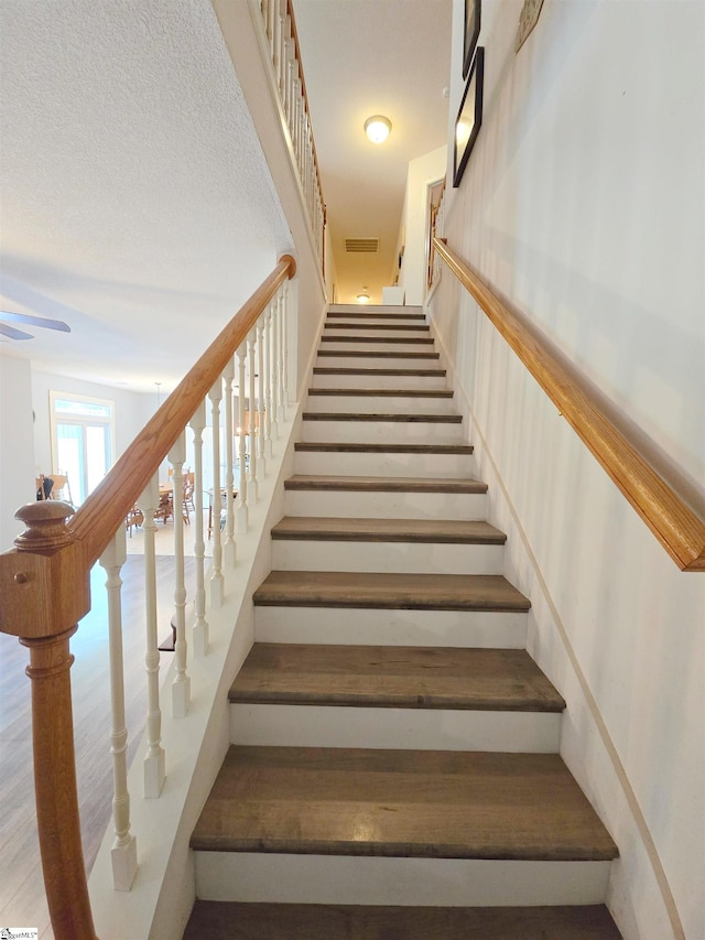 staircase with visible vents and a ceiling fan