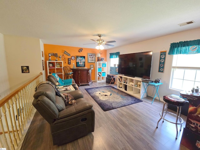 living area featuring a ceiling fan, visible vents, a healthy amount of sunlight, and wood finished floors