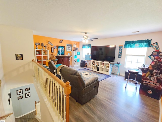 living area featuring visible vents, a ceiling fan, baseboards, and wood finished floors