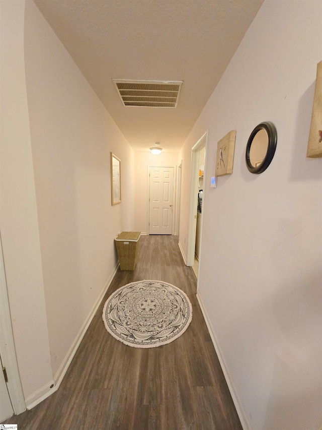 corridor featuring baseboards, visible vents, and wood finished floors