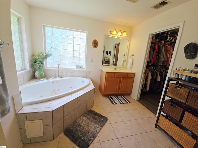 bathroom featuring vanity, tile patterned floors, a jetted tub, a spacious closet, and visible vents