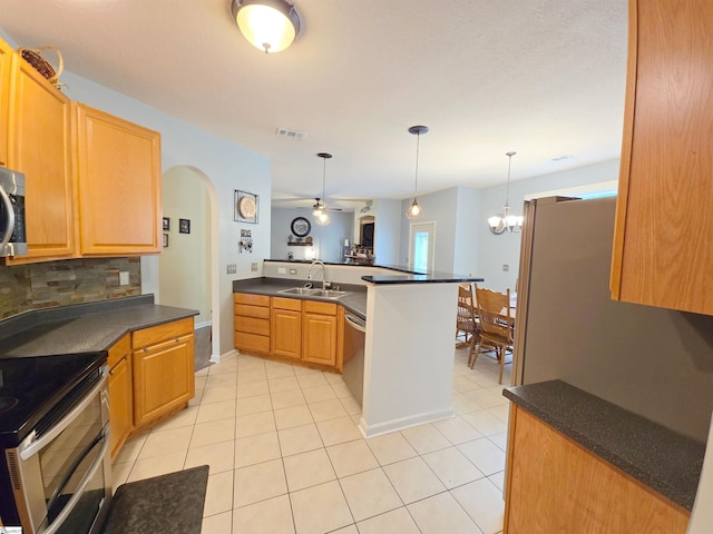 kitchen featuring visible vents, dark countertops, a sink, a peninsula, and stainless steel appliances