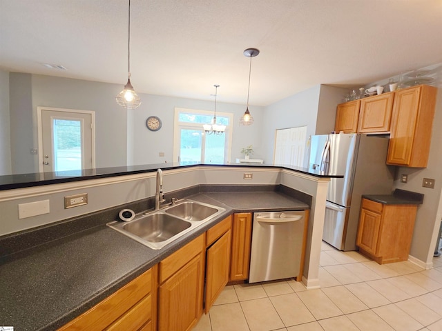 kitchen with a sink, dark countertops, stainless steel appliances, and a healthy amount of sunlight