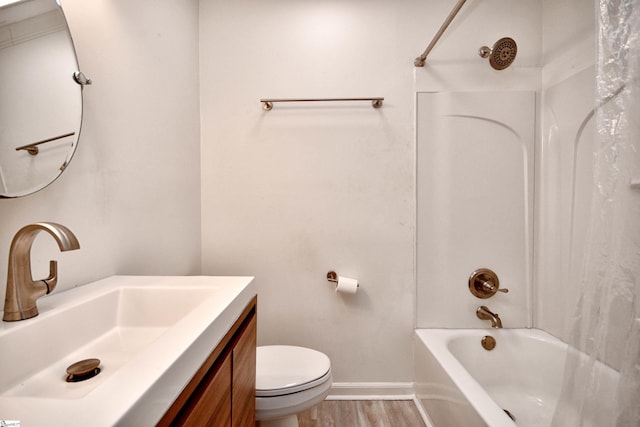bathroom featuring vanity, toilet, baseboards, wood finished floors, and shower / bathing tub combination