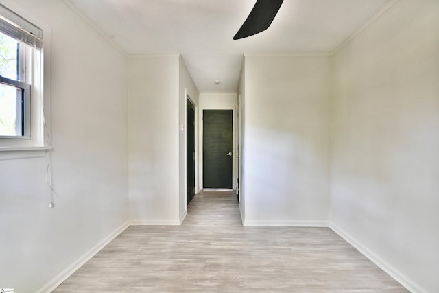 empty room with baseboards, ornamental molding, light wood finished floors, and ceiling fan