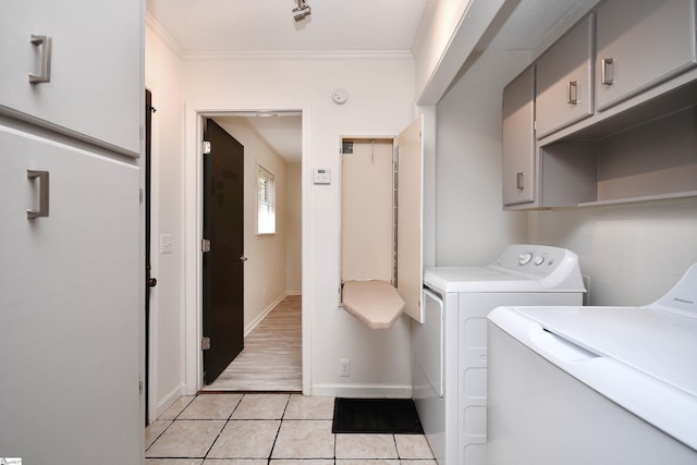 laundry room with crown molding, cabinet space, baseboards, light tile patterned flooring, and washer and dryer