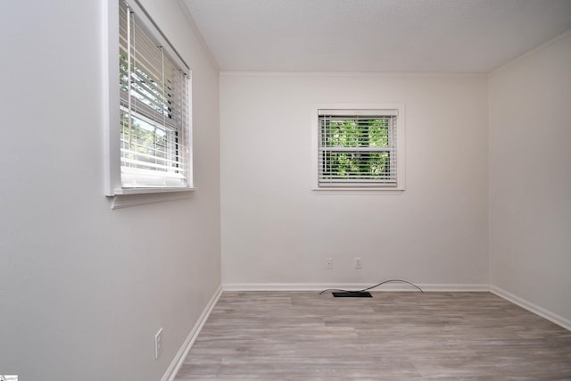 spare room featuring crown molding, baseboards, and wood finished floors