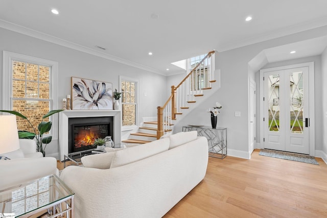 living room with light wood finished floors, a glass covered fireplace, stairs, recessed lighting, and baseboards