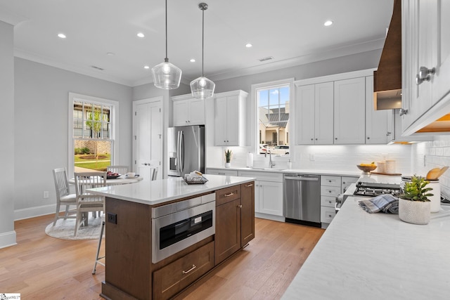 kitchen featuring light countertops, tasteful backsplash, stainless steel appliances, and crown molding