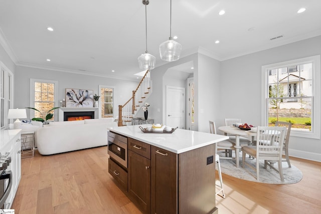 kitchen featuring visible vents, crown molding, light wood-style flooring, and stainless steel microwave