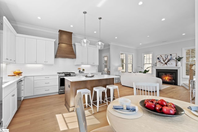 kitchen featuring a center island, appliances with stainless steel finishes, custom exhaust hood, and light wood-type flooring