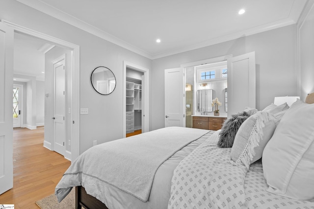 bedroom with crown molding, recessed lighting, a spacious closet, light wood-style flooring, and ensuite bath