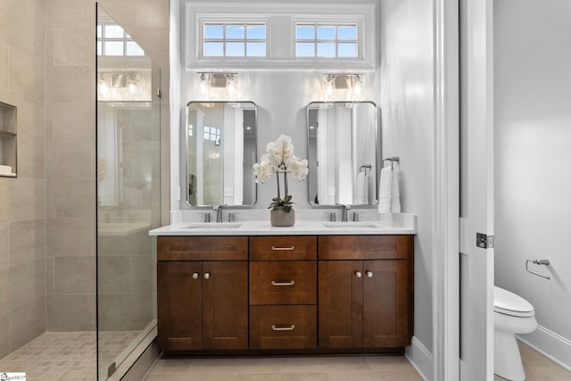 bathroom featuring double vanity, a sink, toilet, and tiled shower