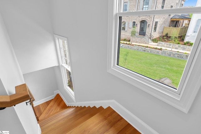 stairway featuring baseboards, plenty of natural light, and wood finished floors