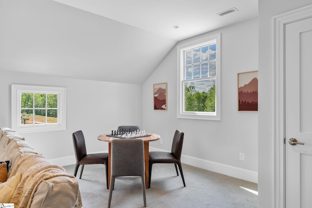 carpeted dining space with visible vents, baseboards, and lofted ceiling