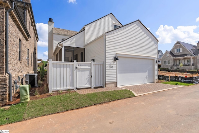 view of home's exterior featuring fence, a gate, central AC unit, and driveway