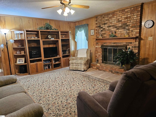 living area with ornamental molding, a brick fireplace, ceiling fan, wooden walls, and a textured ceiling