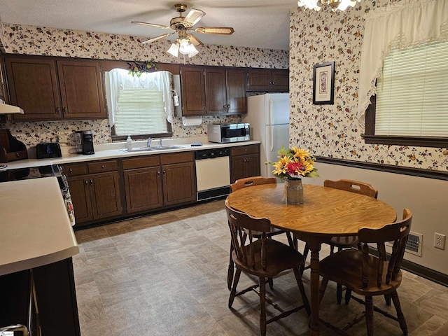 kitchen featuring a ceiling fan, a sink, light countertops, wallpapered walls, and white appliances