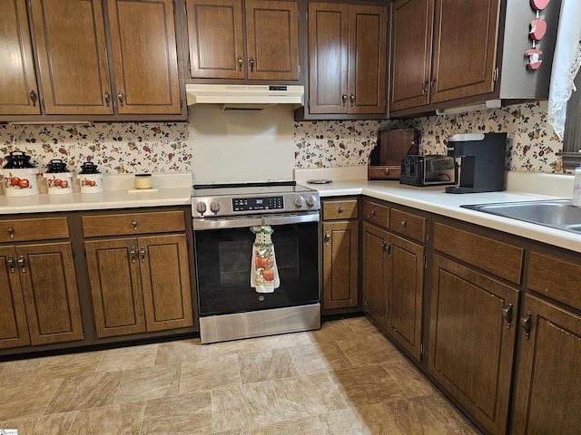 kitchen with light countertops, under cabinet range hood, and stainless steel electric stove