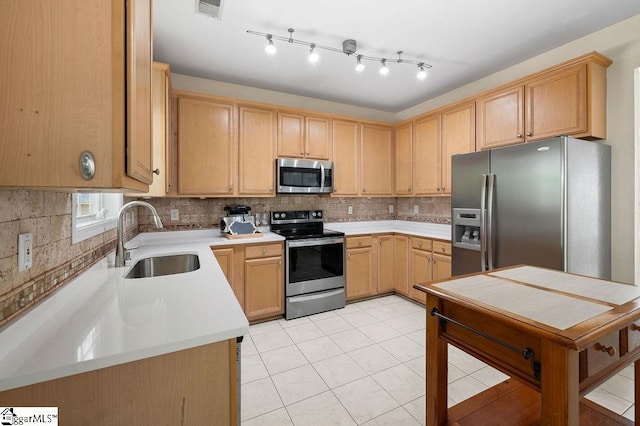 kitchen with light brown cabinetry, appliances with stainless steel finishes, a sink, decorative backsplash, and visible vents