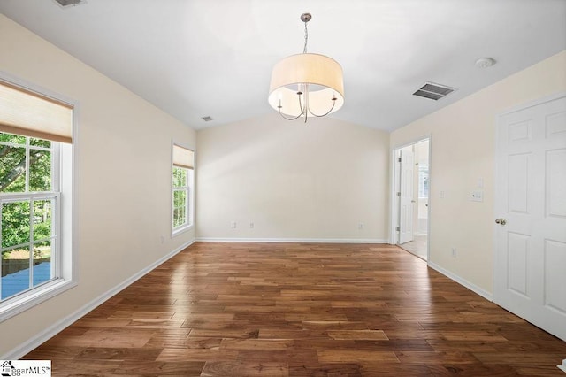 empty room with a wealth of natural light, wood finished floors, and lofted ceiling