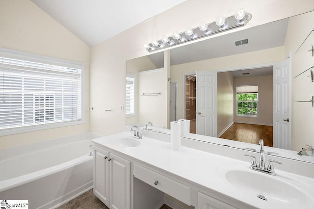 full bath featuring visible vents, a sink, a garden tub, and vaulted ceiling