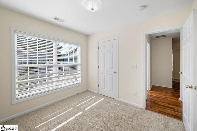 unfurnished bedroom with carpet floors, baseboards, and visible vents