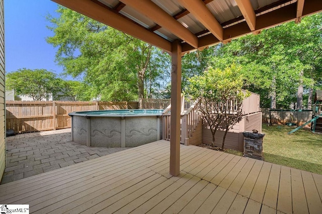 deck with a playground, a fenced in pool, a yard, and a fenced backyard