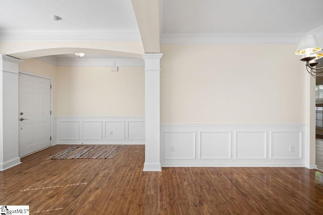 interior space with crown molding, arched walkways, wood finished floors, a wainscoted wall, and a decorative wall