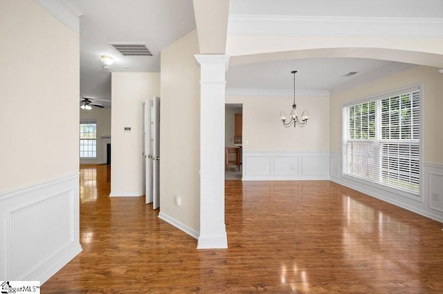 unfurnished dining area featuring arched walkways, visible vents, wainscoting, and wood finished floors