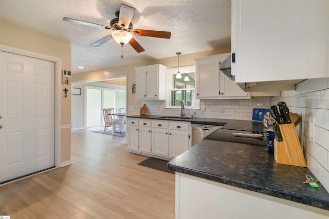 kitchen featuring white cabinetry, a textured ceiling, dark countertops, and a sink