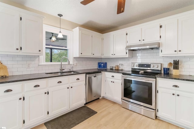 kitchen featuring a ceiling fan, under cabinet range hood, white cabinets, a sink, and stainless steel appliances