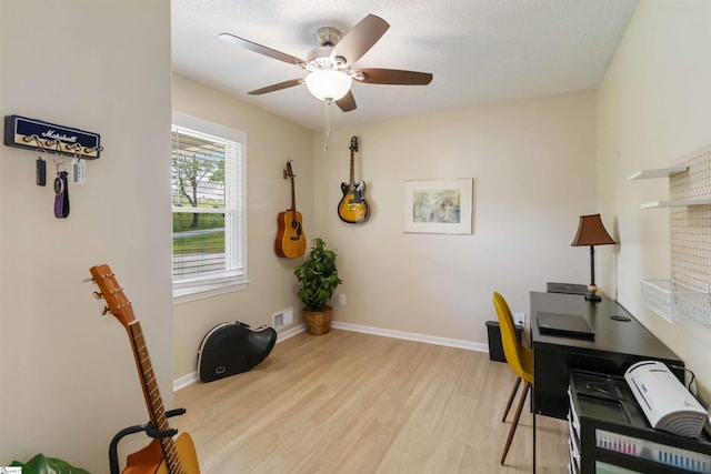 office area featuring baseboards, ceiling fan, light wood-type flooring, and visible vents