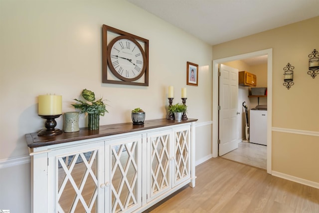 hall with baseboards, light wood-style flooring, and washer / clothes dryer