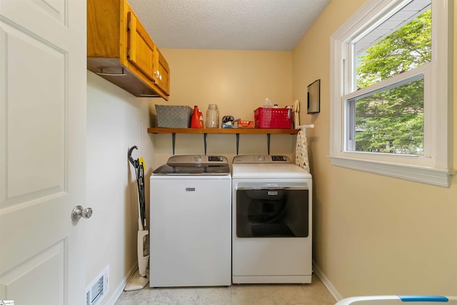 washroom featuring baseboards, washing machine and dryer, cabinet space, and visible vents