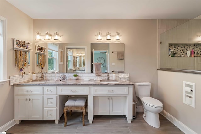 bathroom featuring backsplash, toilet, baseboards, and a sink