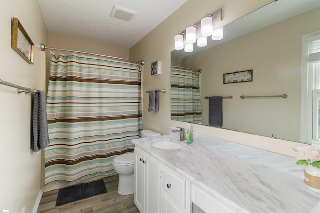 bathroom with visible vents, vanity, wood finished floors, toilet, and a shower with shower curtain