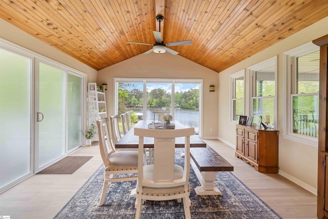 dining room featuring ceiling fan, light wood-style flooring, baseboards, a water view, and vaulted ceiling