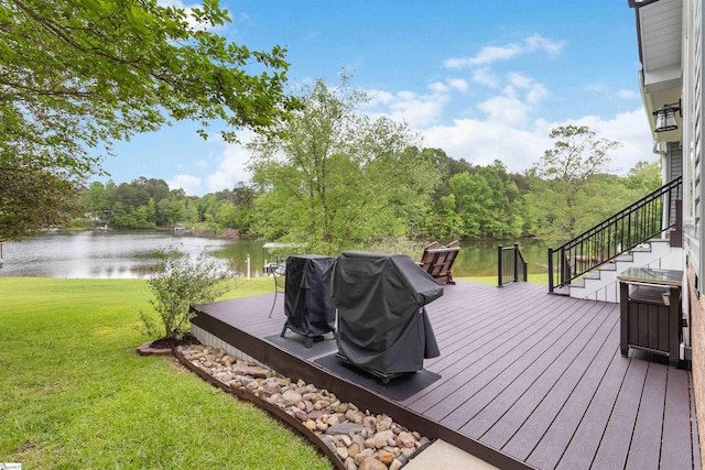 deck featuring stairway, a water view, a forest view, a lawn, and a grill