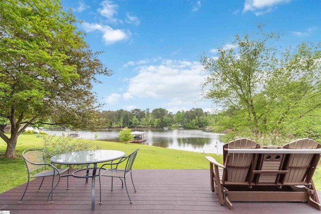 deck with outdoor dining space, a water view, and a yard