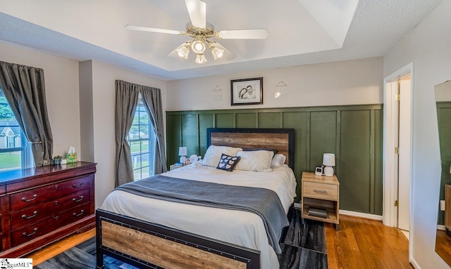 bedroom featuring ceiling fan, wood finished floors, and a fireplace