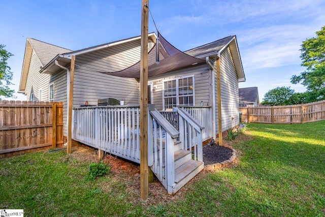 back of property with a fenced backyard, a lawn, and a deck
