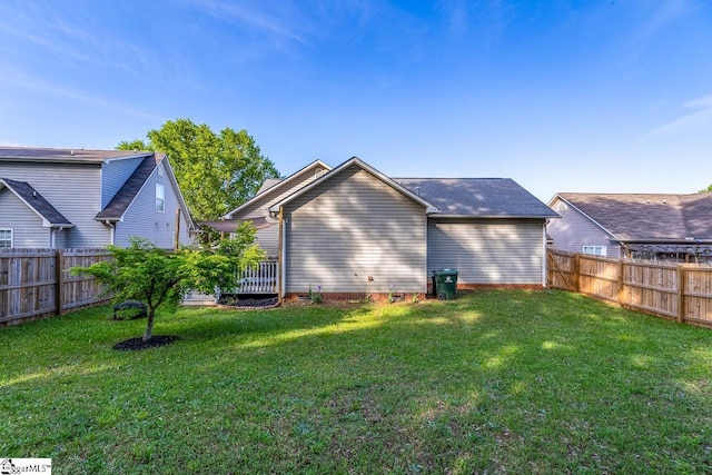rear view of house with a lawn and a fenced backyard