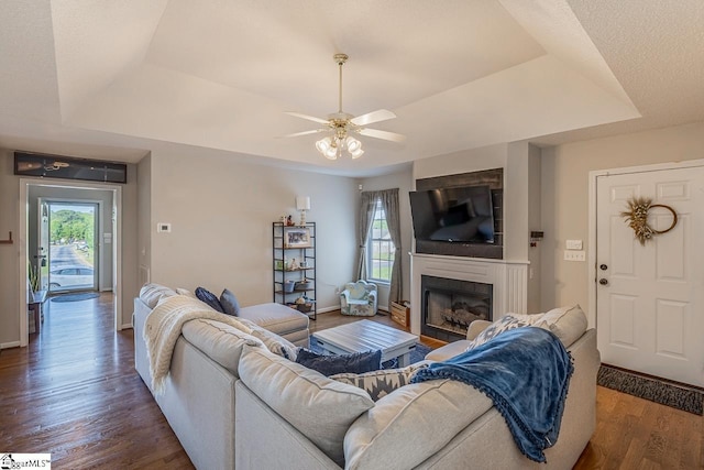 living room featuring a healthy amount of sunlight, a ceiling fan, and a tray ceiling
