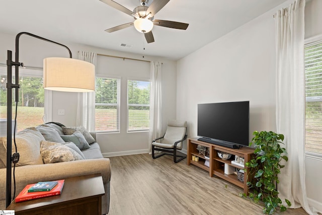 living room featuring baseboards, a ceiling fan, light wood finished floors, and visible vents