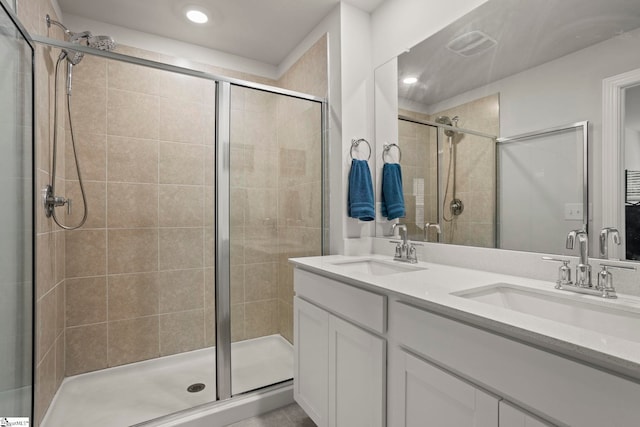 bathroom with a sink, a shower stall, recessed lighting, and double vanity