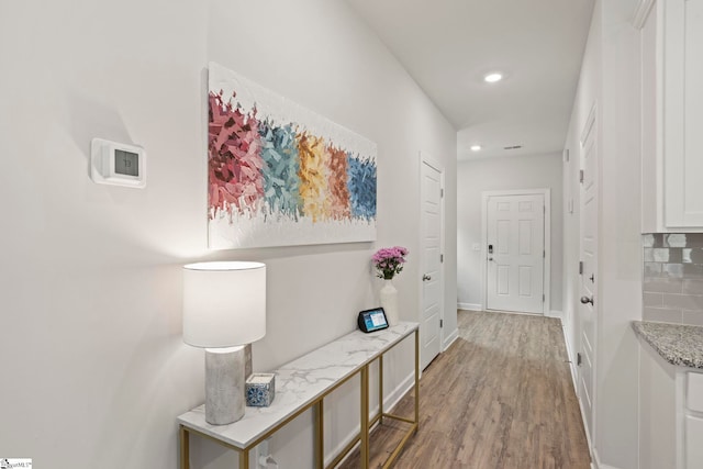 hallway featuring baseboards, recessed lighting, and wood finished floors