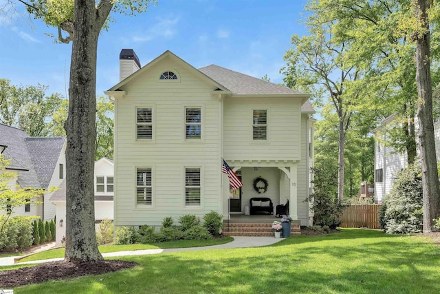view of front facade with a front lawn, fence, and a chimney
