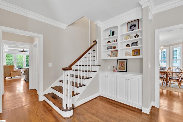 stairs with crown molding, baseboards, and wood finished floors