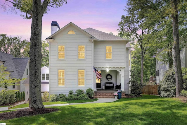 traditional-style home with a lawn, fence, and a chimney